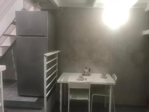 un piccolo tavolo bianco con 2 sedie e un frigorifero di CASA VERGINELLE SHORT LETS a Catania