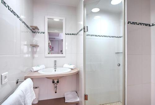 La salle de bains blanche est pourvue d'un lavabo et d'une douche. dans l'établissement Hôtel Club la Font des Horts, à Hyères