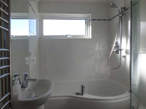 a bathroom with a sink and a tub and a shower at Godolphin in Wadebridge