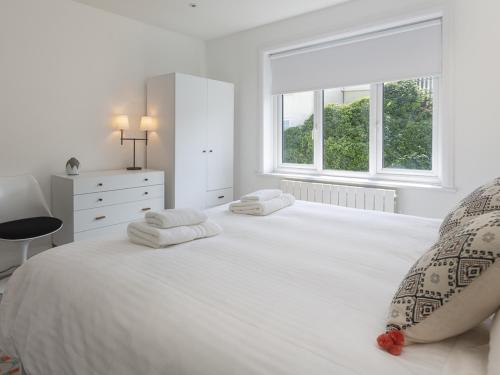 een witte slaapkamer met een groot wit bed met 2 kussens bij 3 Church Hill House in Salcombe