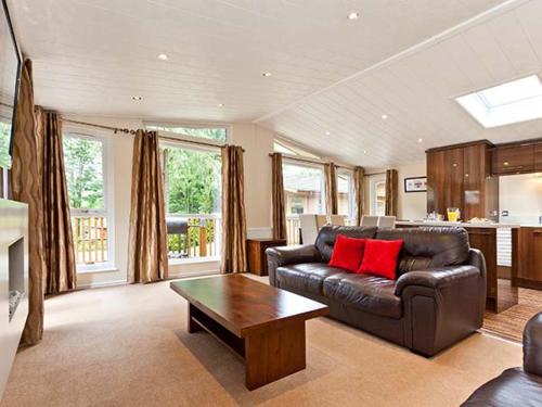 un soggiorno con un divano in pelle e un tavolo di Beech Hill Lodge Beech Hill 9 at Fallbarrow Park a Windermere