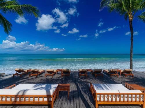a wooden deck with chairs and the ocean at The Legian Seminyak, Bali in Seminyak