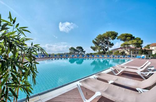 a swimming pool with two lounge chairs next to it at Hôtel Club la Font des Horts in Hyères