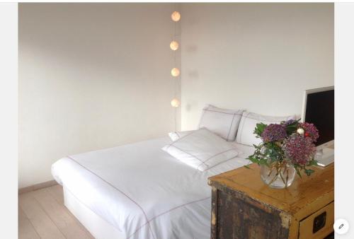 a bedroom with a bed and a vase of flowers on a table at Aux 4 Sardines T2 56m2 in Concarneau