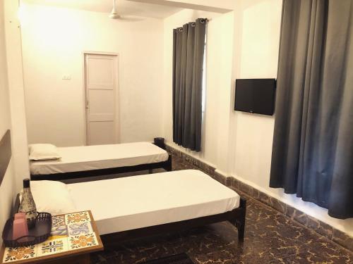 a room with two beds and a mirror at Hotel Paulino in Madgaon