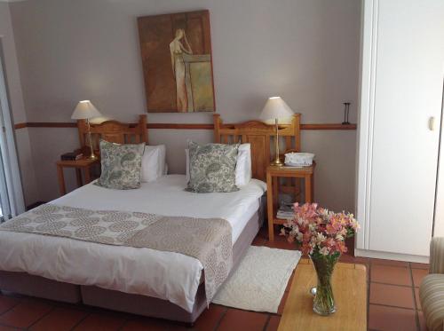 a bedroom with a bed and a vase of flowers at Chez Esme Guest House in Roodepoort