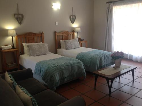 a living room with two beds and a couch at Chez Esme Guest House in Roodepoort