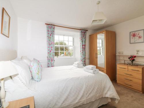 a bedroom with a large white bed and a window at Penrose Farm Cottage in Saint Keverne