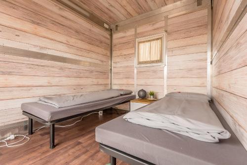 two beds in a room with wooden walls at Oktoberfest Wiesn Camp Lodge in Munich