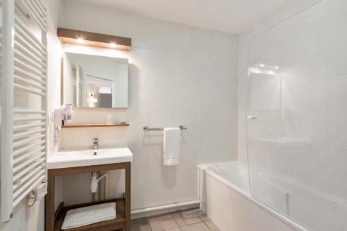 a white bathroom with a sink and a shower at Appart'City Confort Mulhouse in Mulhouse
