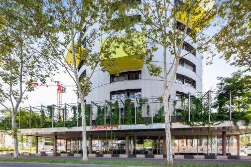 a white building with trees in front of it at Appart'City Confort Mulhouse in Mulhouse