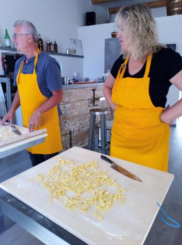 two people in a kitchen preparing pasta on a cutting board at L'armonica di nonnoSandro in Corfinio