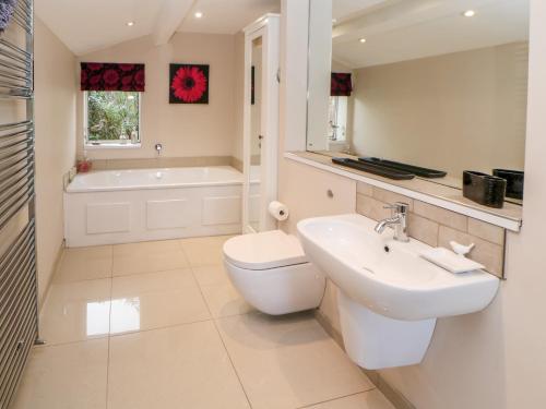 een badkamer met een wastafel, een toilet en een bad bij Berrymoor Cottage in Brampton