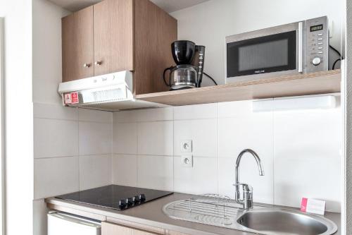 a small kitchen with a sink and a microwave at Appart'City Confort Mulhouse in Mulhouse