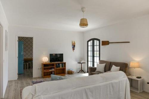 a white living room with a couch and a tv at Altura LP Sunny House in Altura