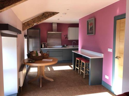 a kitchen with pink walls and a table in a room at Lady Charlotte's Loft in Schull
