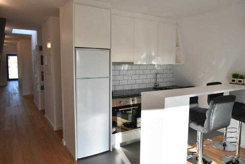 a kitchen with white cabinets and a white refrigerator at Sunny Penthouse whith balcony 9min walk main station in Porto