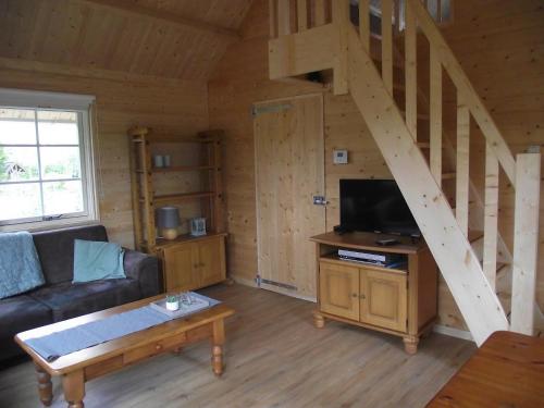 sala de estar con sofá y escalera de madera en Vakantiehuisjes Landgoed Sonneborghe, en Kollumerzwaag