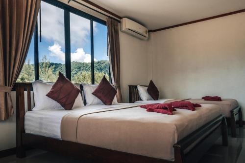 two beds in a room with a large window at Phra Ae Apartments in Ko Lanta