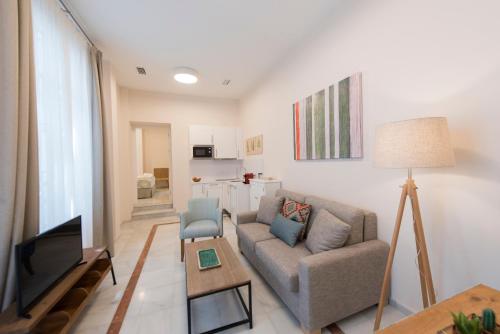 a living room filled with furniture and a tv at Céntriko Apartments - Quintero 40 in Seville