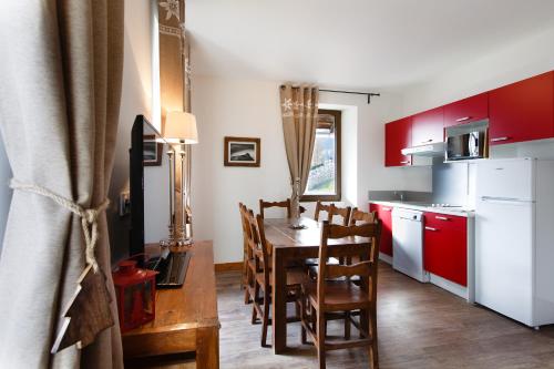 a kitchen with red cabinets and a table and chairs at ETOILE LODGE in Hauteluce