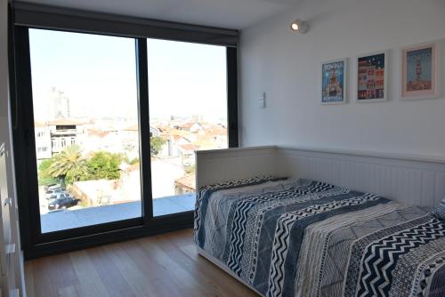 a bedroom with two beds and a large window at Sunny Penthouse whith balcony 9min walk main station in Porto