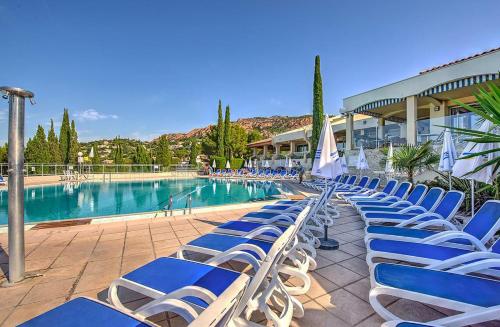 - une rangée de chaises bleues à côté de la piscine dans l'établissement Village Club Les Mas de L'Esterel, à Agay