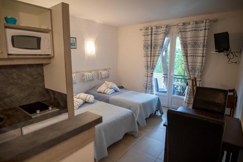ル・プラデにあるLa Bastide des Pinsのベッド2台と電子レンジが備わるホテルルームです。