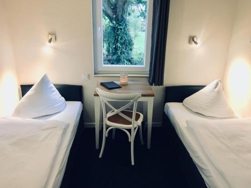 a room with two beds and a table and a chair at Arcade Hotel & Hostel Hamburg in Hamburg