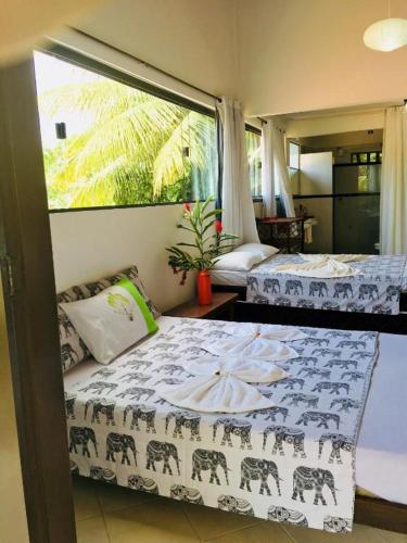 a bedroom with two beds and a large window at Casas Coloniais in Morro de São Paulo