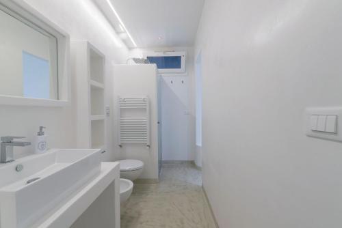 een witte badkamer met een toilet en een wastafel bij Villa Niraclò by Raro Villas in Carovigno