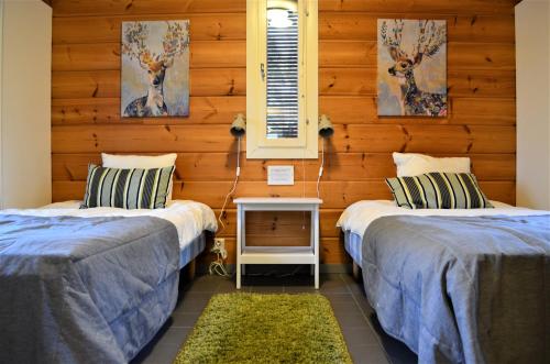two beds in a room with wooden walls at Rauhalahti Holiday Homes in Kuopio