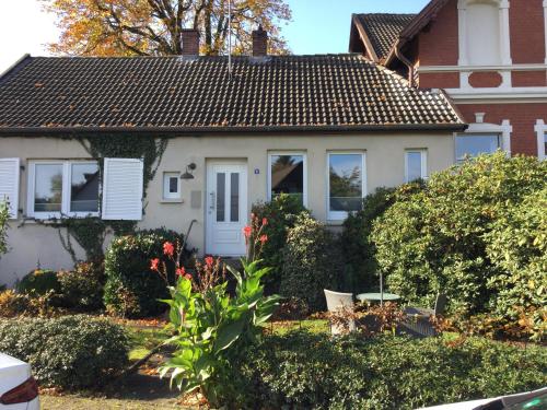 ein weißes Haus mit braunem Dach in der Unterkunft Ferienhaus Us lütt Hus und das Zimmer Linde im Haupthaus in Oldenburg