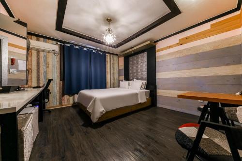 a bedroom with a bed and a desk and a table at Manhatan Hotel 청주 in Cheongju