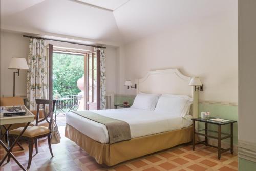 a bedroom with a bed and a desk and a window at QC Termeroma Spa and Resort in Fiumicino