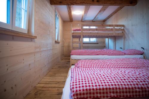 a room with three bunk beds in a cabin at Restaurant und Kaeserei Berghof in Ganterschwil