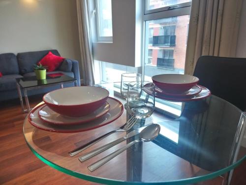 a glass table with two bowls and silverware on it at 1 Bedroom Flat in Sheffield City Centre-Sleeps 4 in Sheffield
