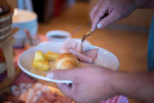 a person eating a plate of food with a fork and knife at Restaurant und Kaeserei Berghof in Ganterschwil