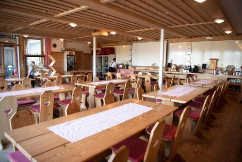 un ristorante vuoto con tavoli e sedie in legno di Restaurant und Kaeserei Berghof a Ganterschwil