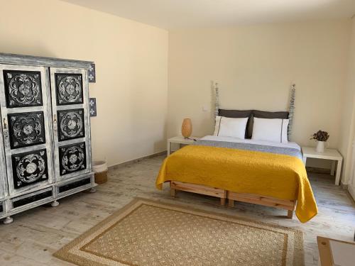 a bedroom with a bed with a yellow blanket and two dressers at Quinta Ribeira do Labrador - Lisbon West Wine Route in Alenquer