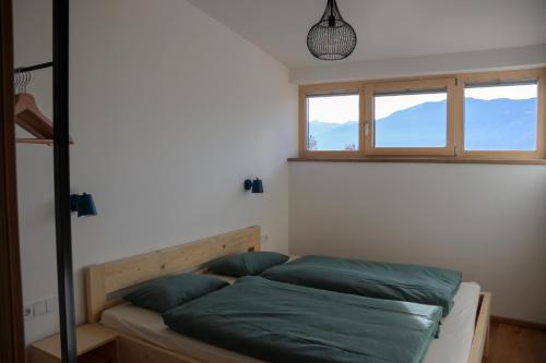 a bedroom with a bed with green sheets and two windows at Biobauernhof Jagglhof in Saalfelden am Steinernen Meer