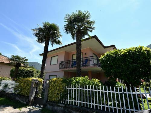 una casa con palmeras y una valla blanca en Belvilla by OYO Cherry House, en Mergozzo