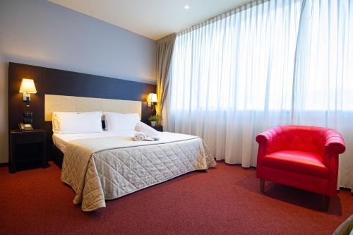 a hotel room with a bed and a red chair at Tuscany Inn in Montecatini Terme