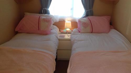 twee bedden in een kleine kamer met een raam bij Sunspot Brixham in Brixham