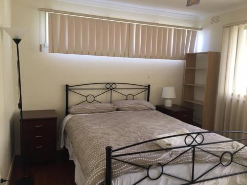 a bedroom with a large bed with a black frame at A1 Holiday home close to train station in Mitcham
