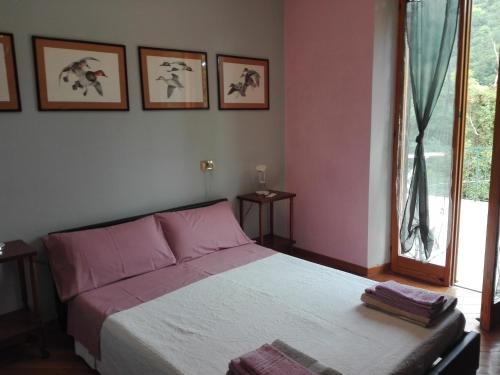 a bedroom with a bed with pink walls and a window at La Torretta bed & breakfast in Torriglia