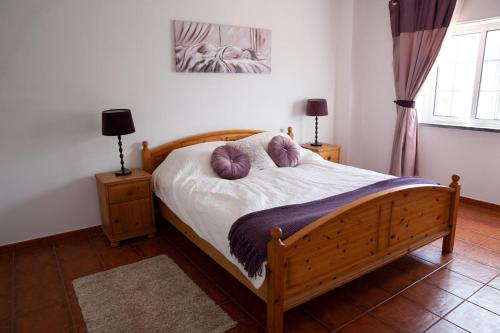 ein Schlafzimmer mit einem Holzbett mit Kissen darauf in der Unterkunft Quinta Turki Malika in Óbidos