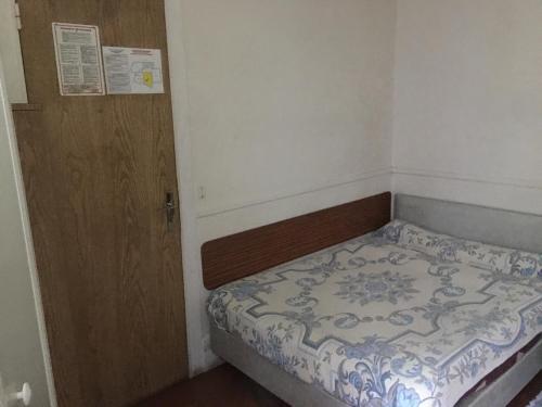 a small bedroom with a bed and a wooden door at A la Pinte du Nord in Paris