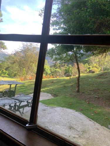 a window looking out at a park with a picnic table at Pousada Quinta das Nascentes in Petrópolis
