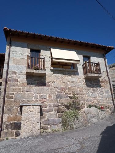 a stone building with two windows and two balconies at Apartamento Carballo Do Xurès in Maus de Salas